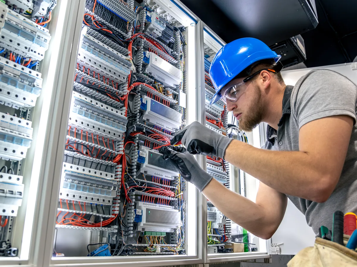 An electrician working inside a large distribution board