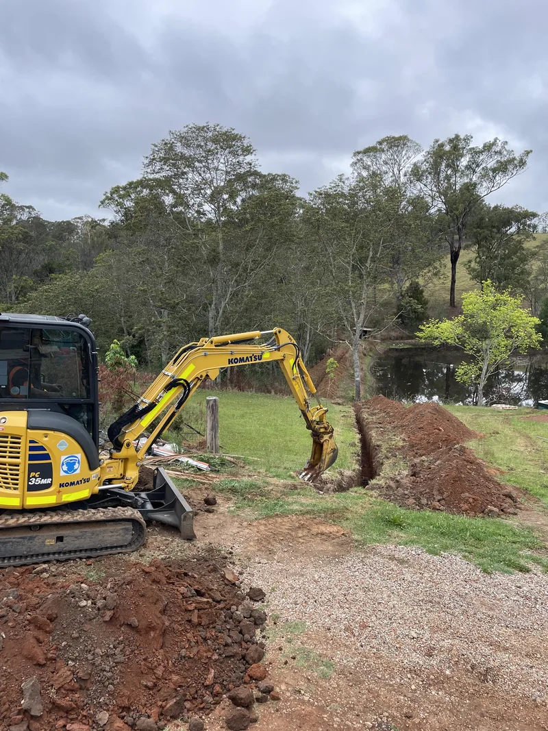 An excavator cutting the trench for the underground mains across the paddock