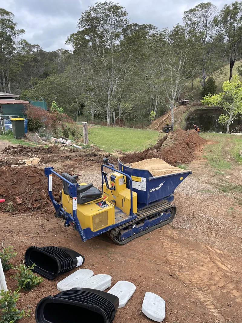 Coils of conduit and the cable pits set out on site beside the tracked dumper