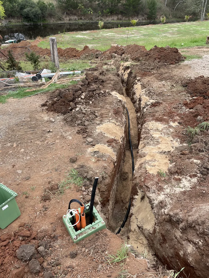 Conduit laid along the floor of the open trench, with a cable pit at the joint