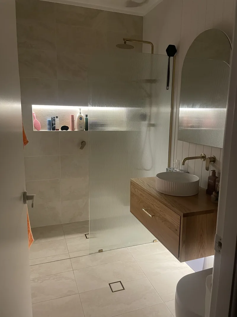 After: the finished bathroom with the lit wall niche and the downlights on