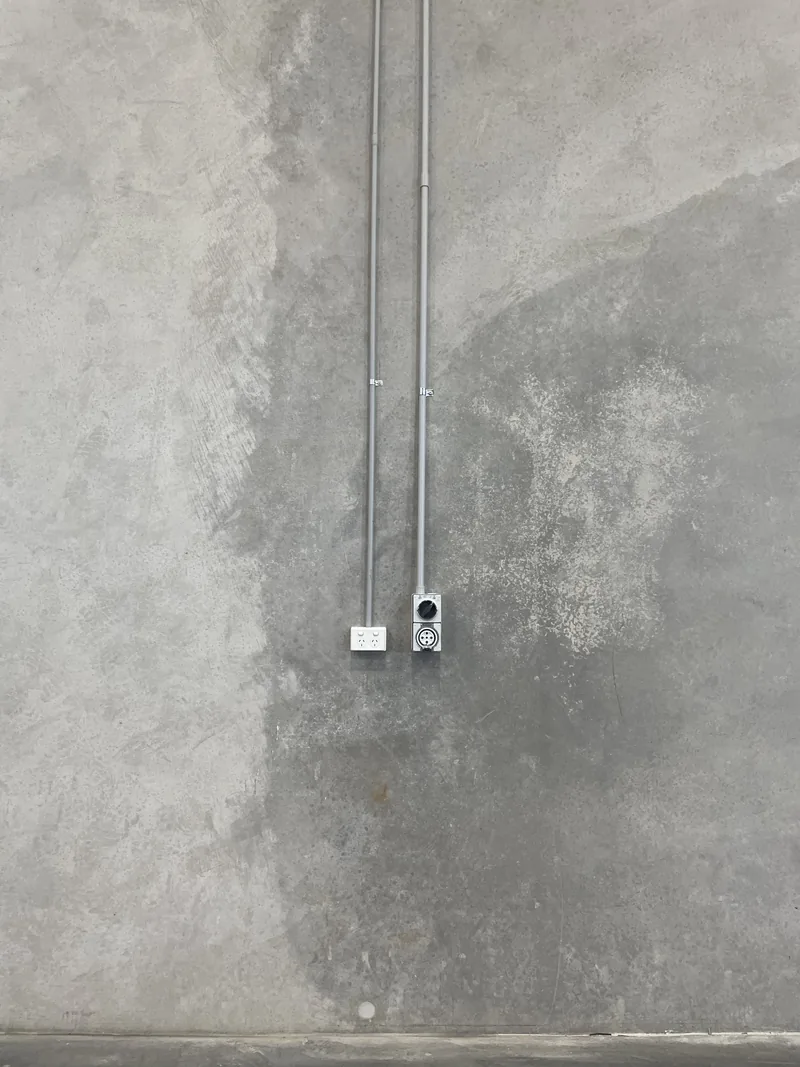 A power outlet fed by a surface conduit drop on a precast panel