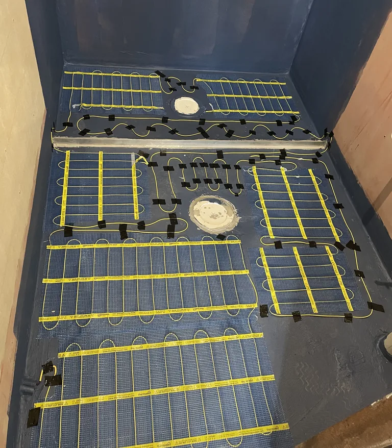 Electric underfloor heating laid out across a bathroom floor before the tiles go on